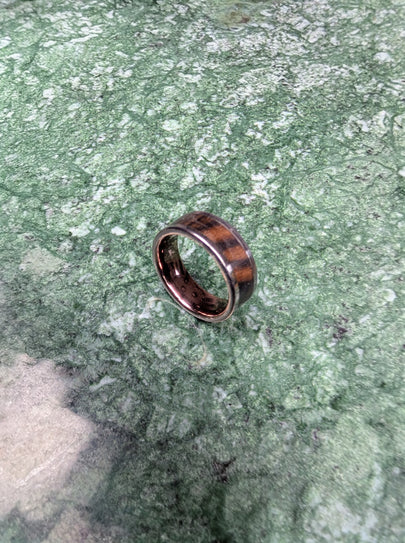 Ring with wooden inlay on a green stone surface